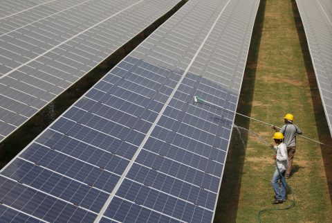 Workers clean photovoltaic panels inside a solar power plant in Gujarat. Can rethinking risk accelerate the Global South's energy transition?
