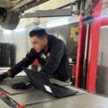 Man leans over large depleted EV battery in a workshop in Amman